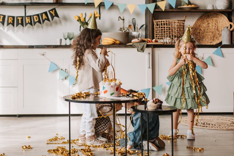Children having fun at a birthday party with decorations and cake indoors.